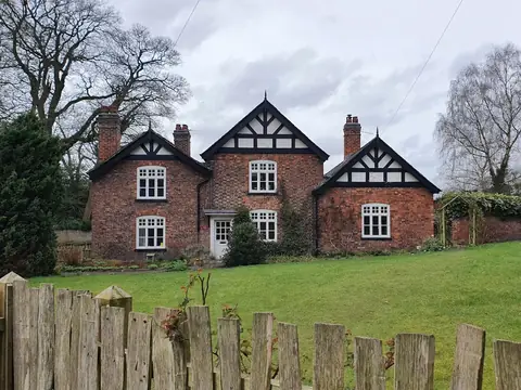 A traditional English brick house with a garden and wooden fence