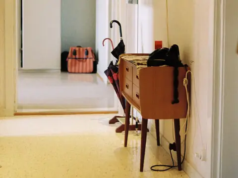 A hallway with a side table, umbrella and suitcase, ready for a trip